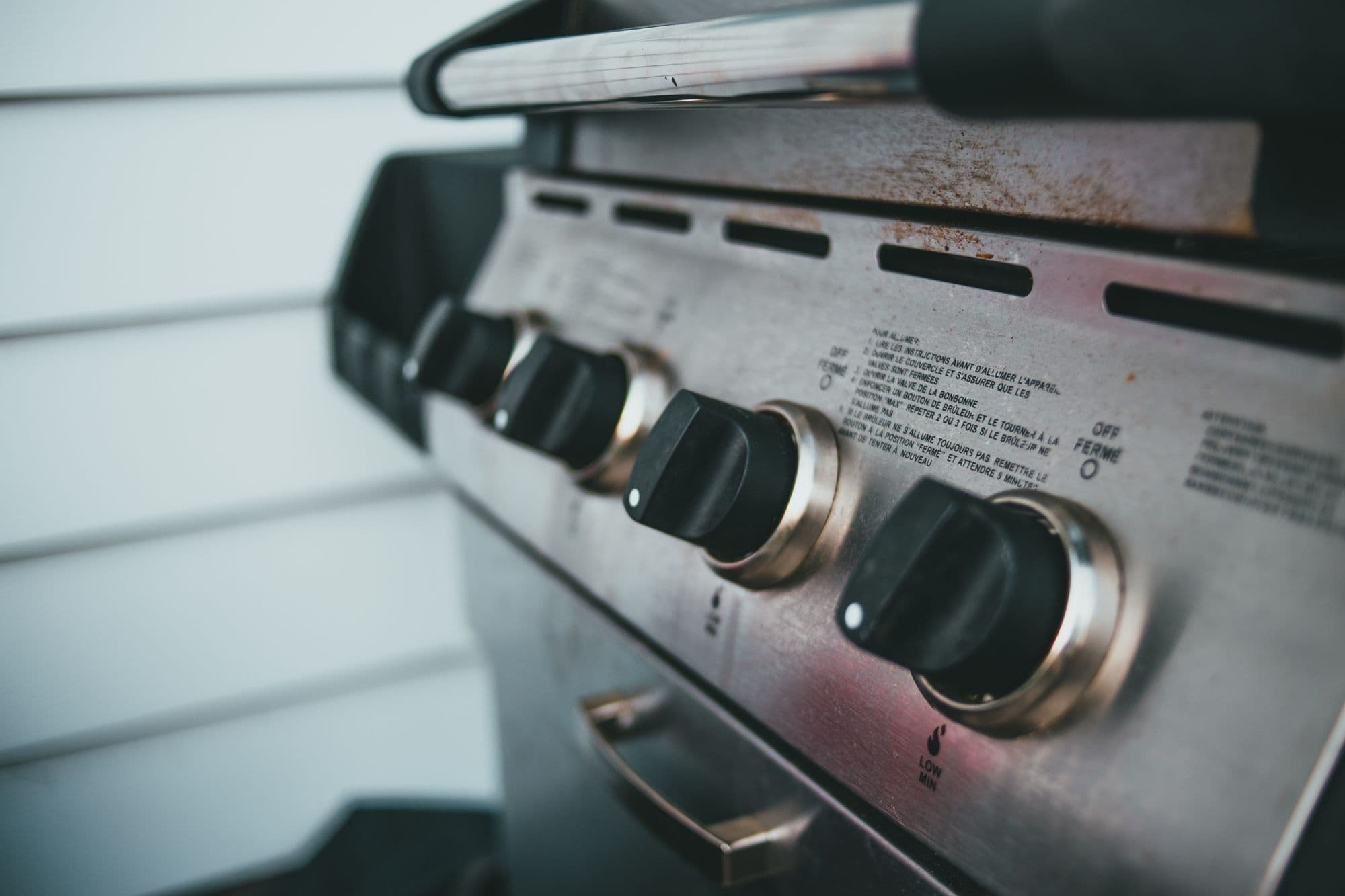 Close-up of the black control knobs on a stainless steel gas grill front panel