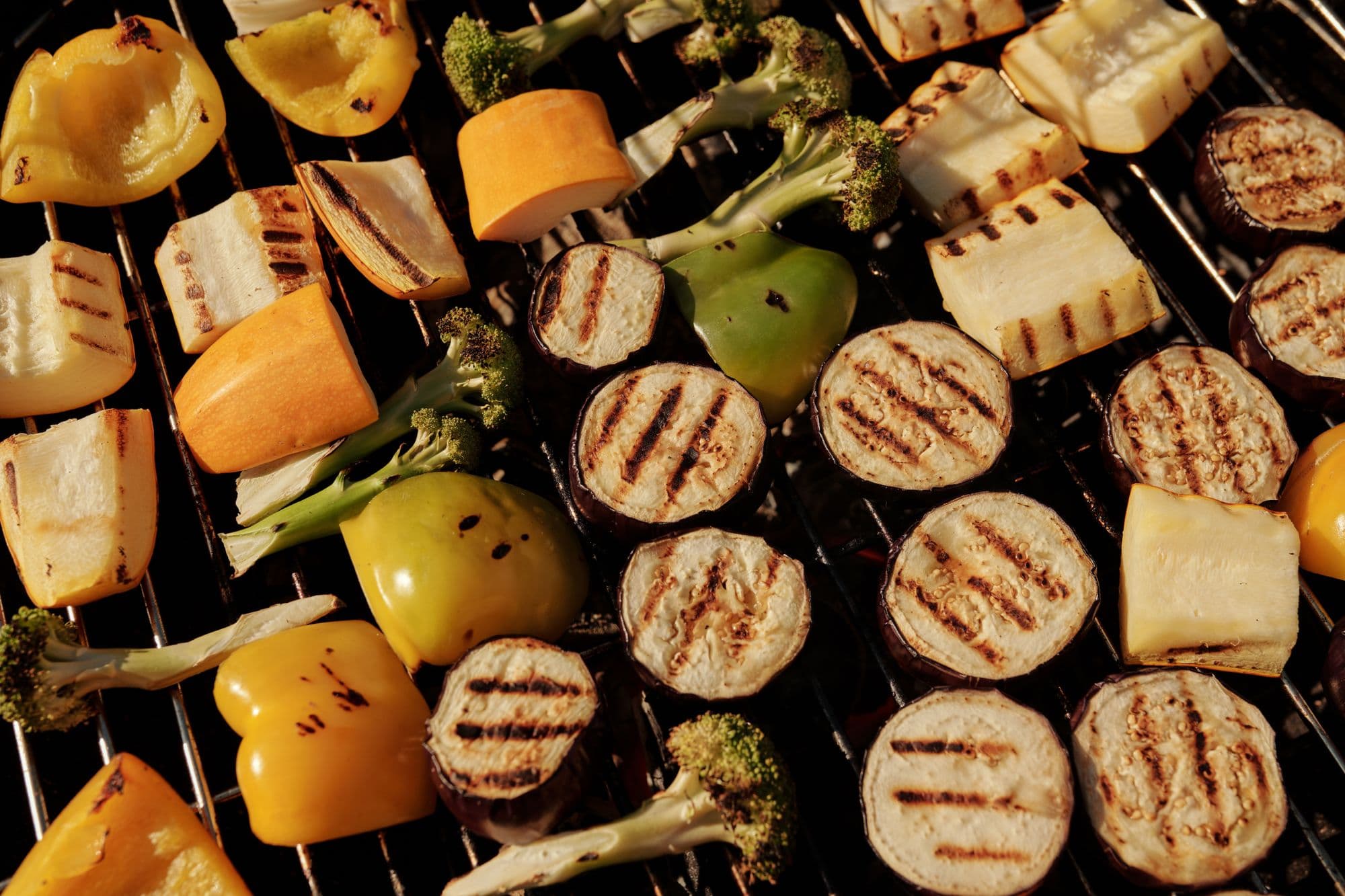 Overhead view of grilled eggplant, peppers, squash and broccoli on a grill grate